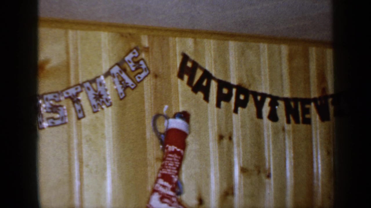 Wood-paneled wall with partial CHRISTMAS garland, HAPPY NEW YEAR banner, and red stocking.