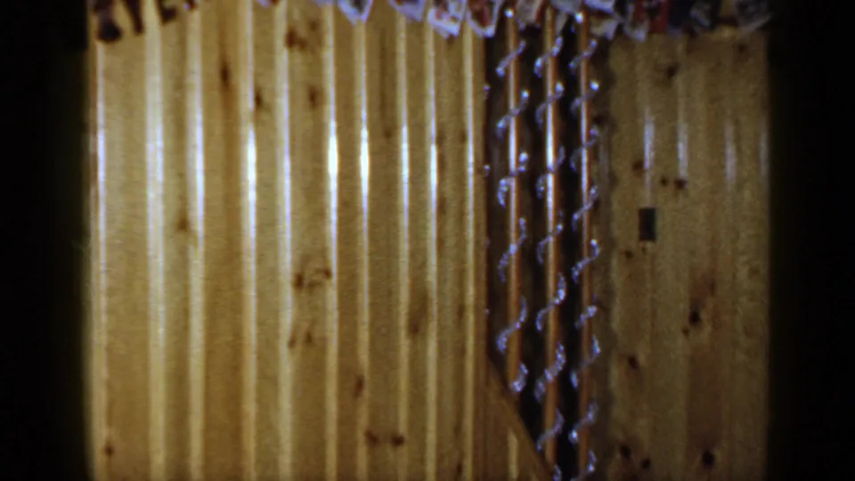 Final 1965 Long Island frame emphasizing wood paneling, hanging tinsel, and the edge of the holiday card display.