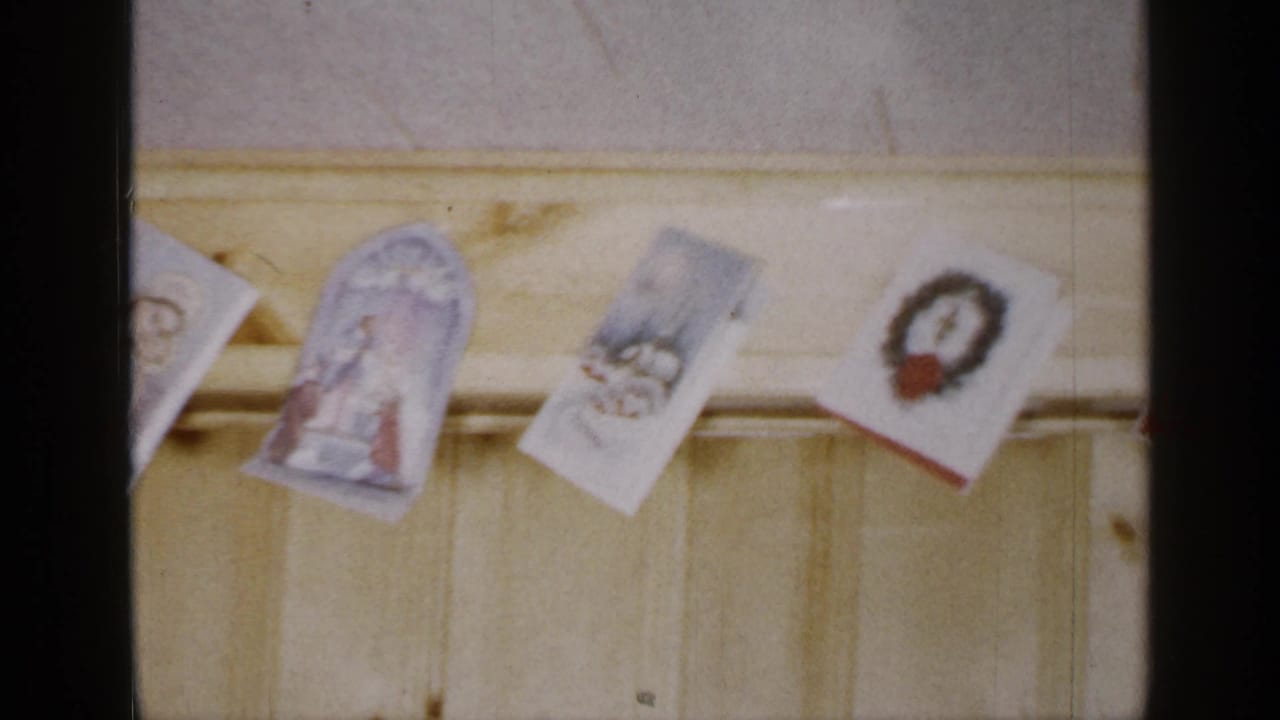 Christmas cards hanging from a pale wooden beam above light wall paneling.