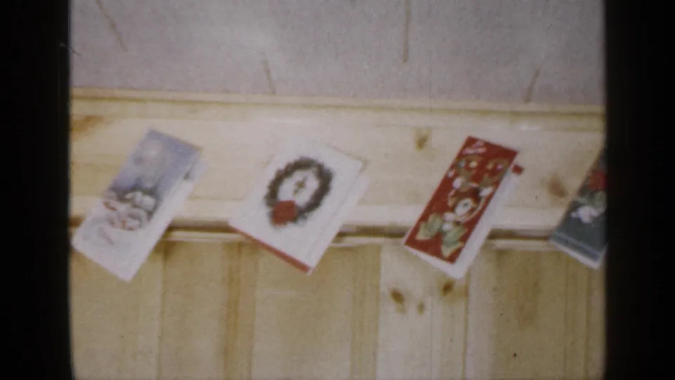 A row of Christmas cards continues across the pale wooden beam in the Long Island interior, with wreath artwork and a red illustrated card visible.