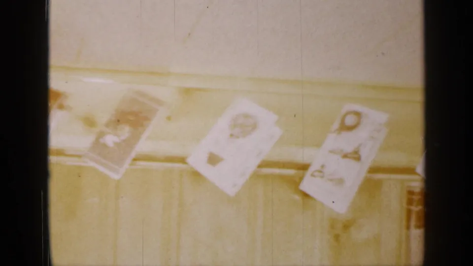 The pan reaches lighter Christmas cards hanging from the same pale beam in the Long Island home, with faded color and visible 8mm frame edges.