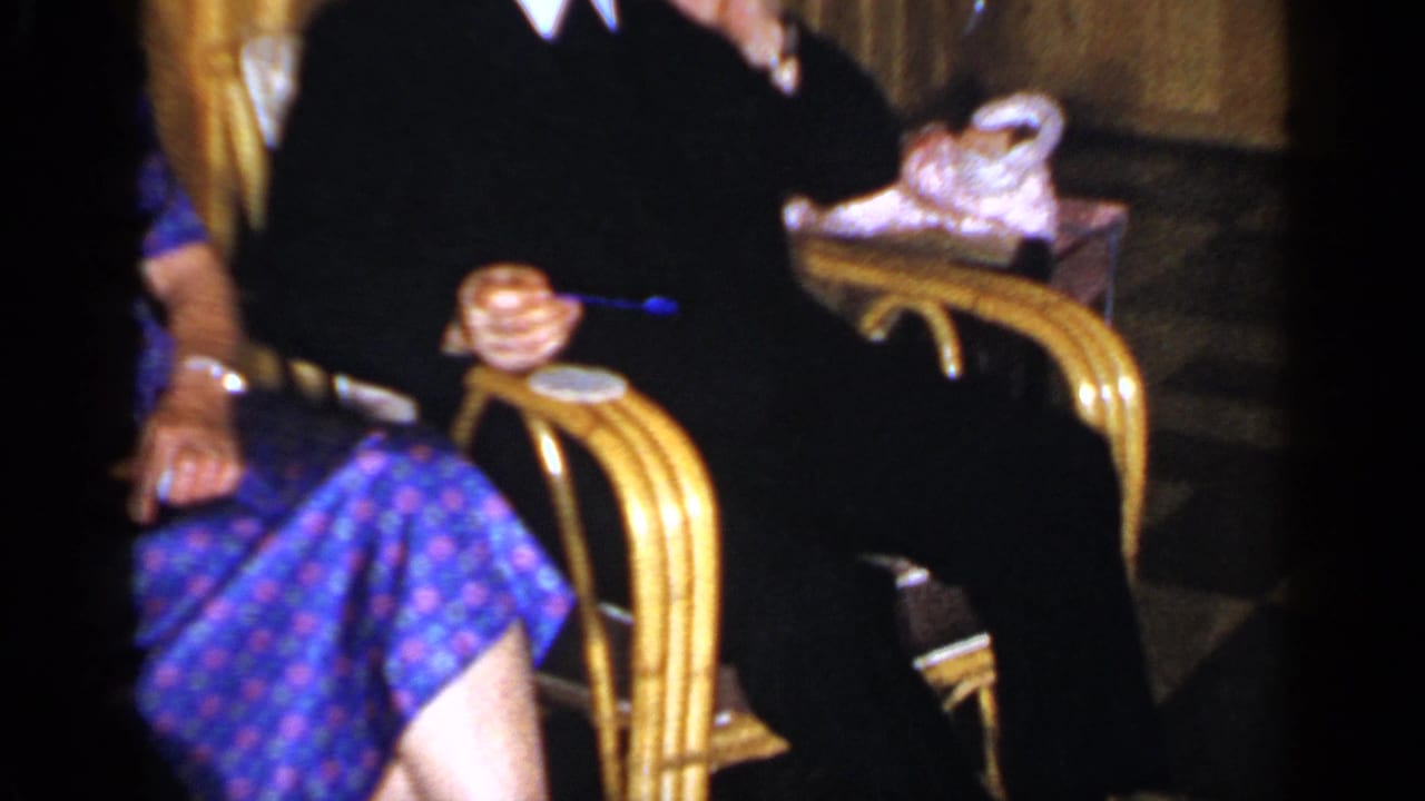 Adults seated in wicker chairs with drinks visible near gold curtains.