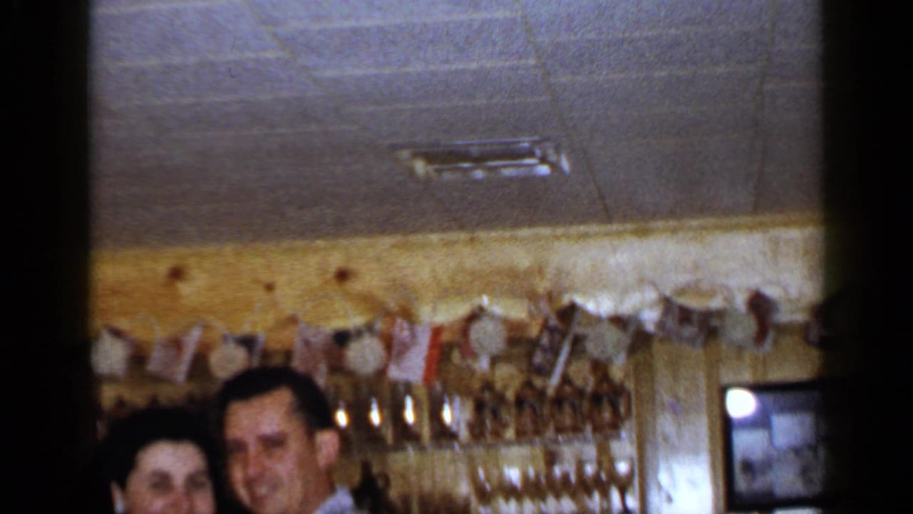 Two adults partly visible at the bottom of a wood-paneled bar interior.