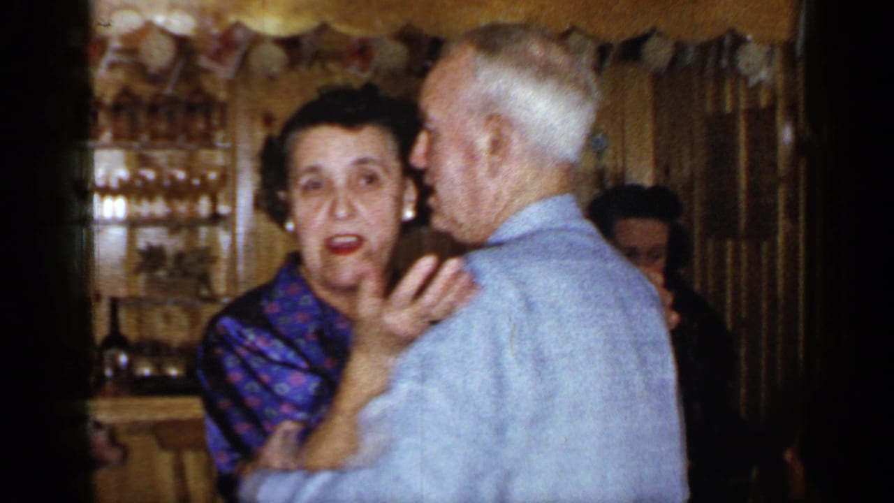 Older couple dancing indoors, with the woman facing the camera and the man turned partly away.