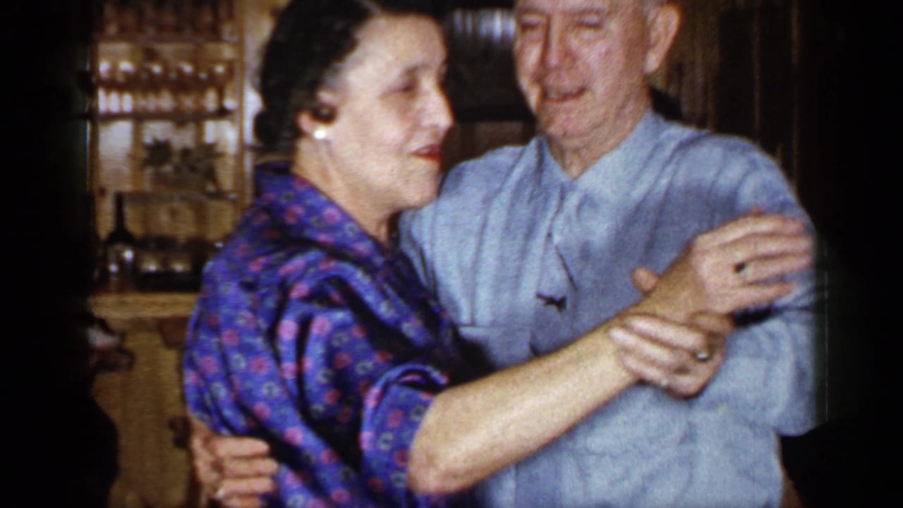 Older woman and man dance together, smiling as they hold each other in a close ballroom-style position.