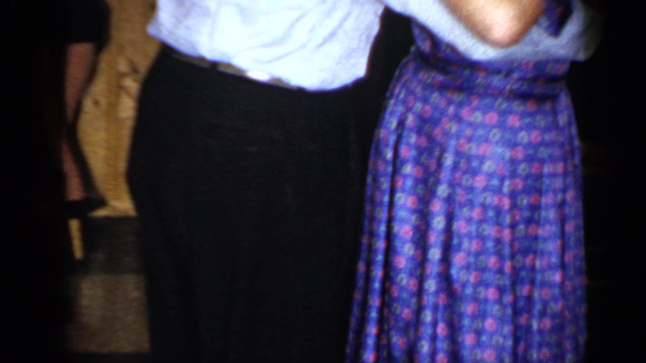 Cropped view of a couple dancing indoors with other guests nearby.