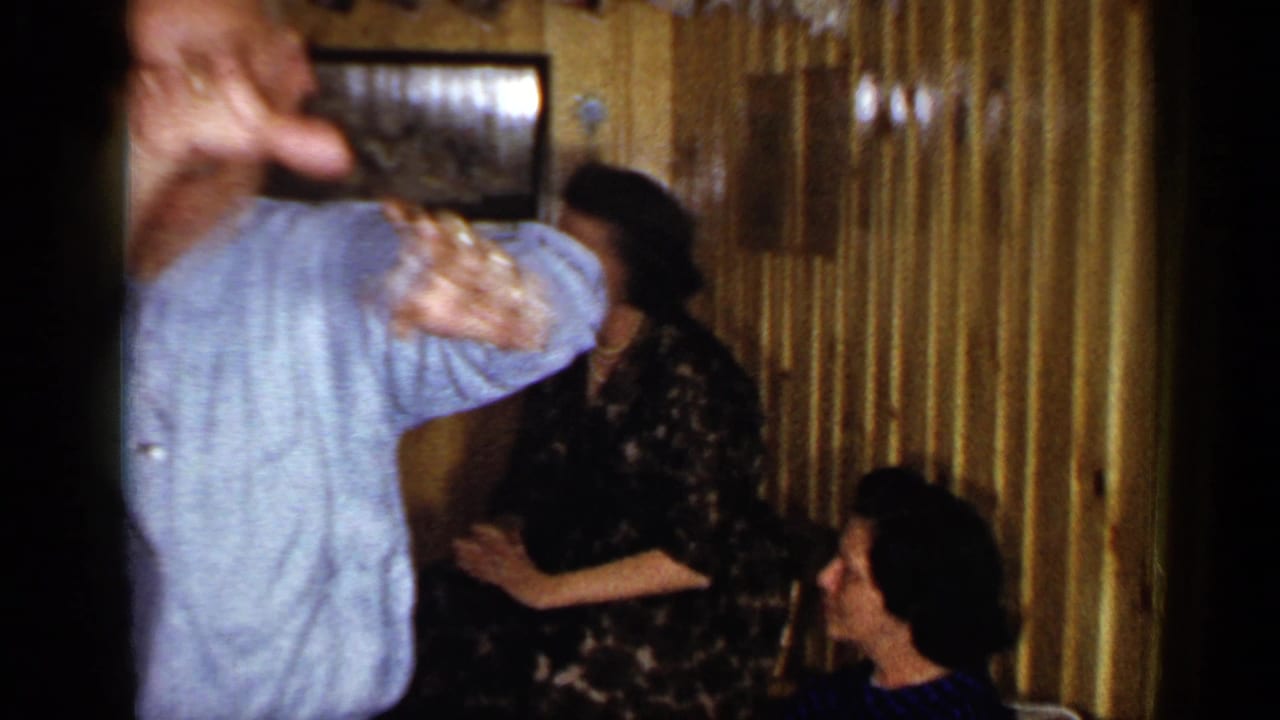 Adults dancing and sitting inside a wood-paneled bar interior.