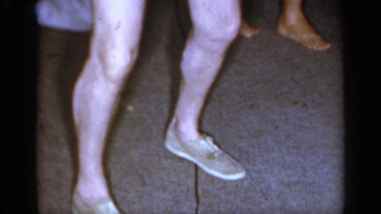 Lower legs of adults dancing on carpet in a private room.
