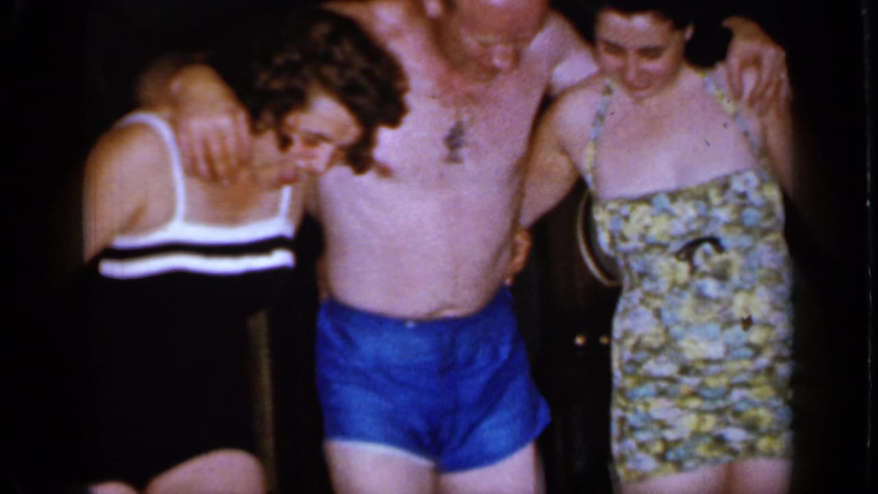 The swimsuit trio shifts position in the 1966 Mineola home movie, with the man centered and both women close at his sides.