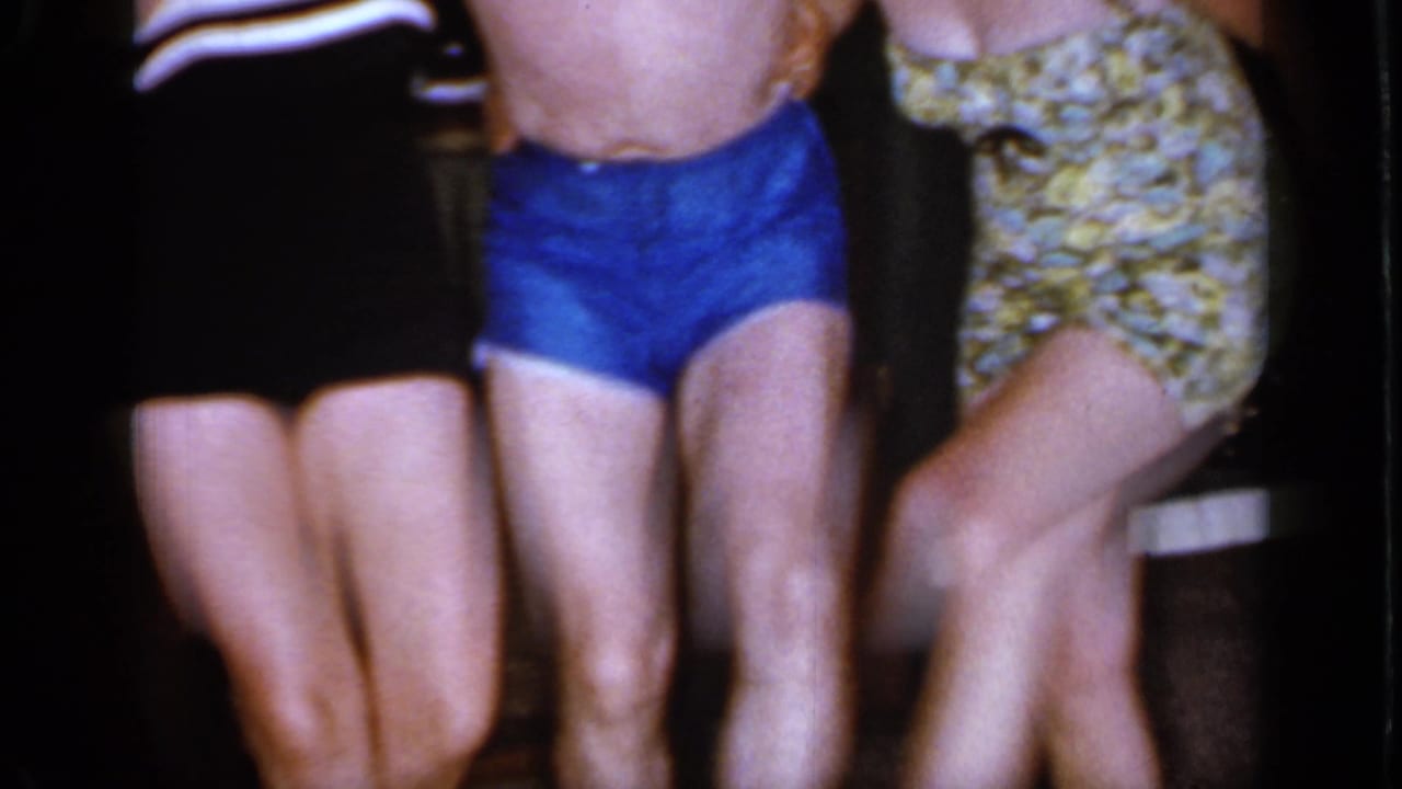 Adults in swimsuits shown from the waist down as they move their legs indoors.