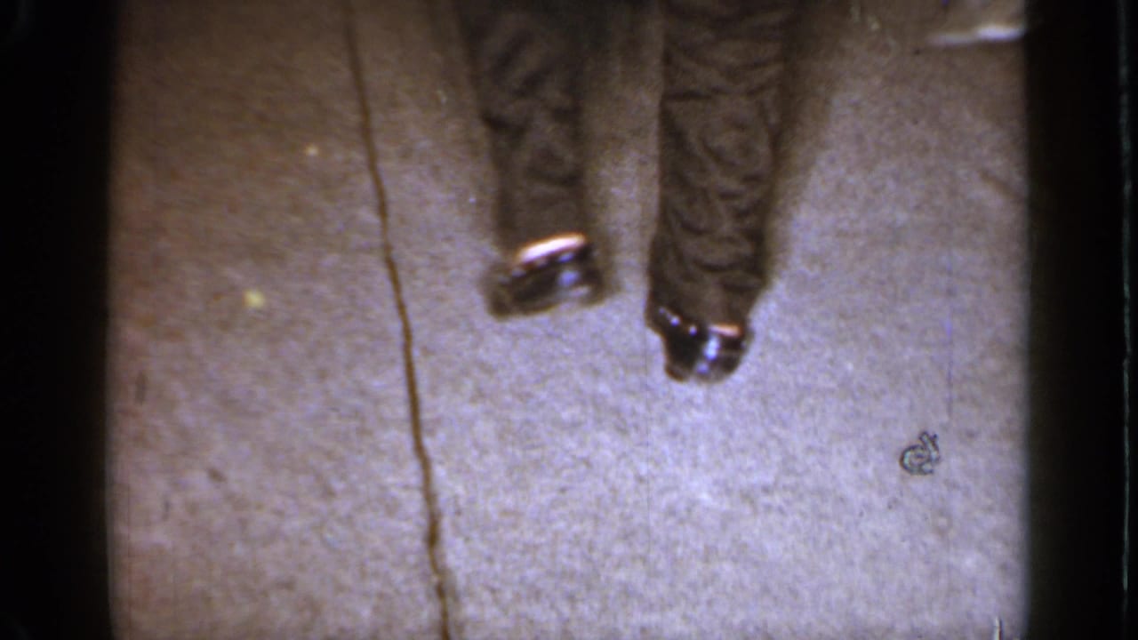 Lower legs on carpet with a small object lying on the floor.