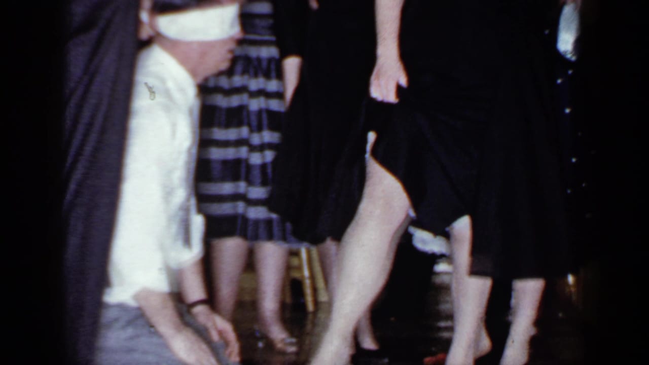 Blindfolded man crouches near standing guests during an indoor party game.