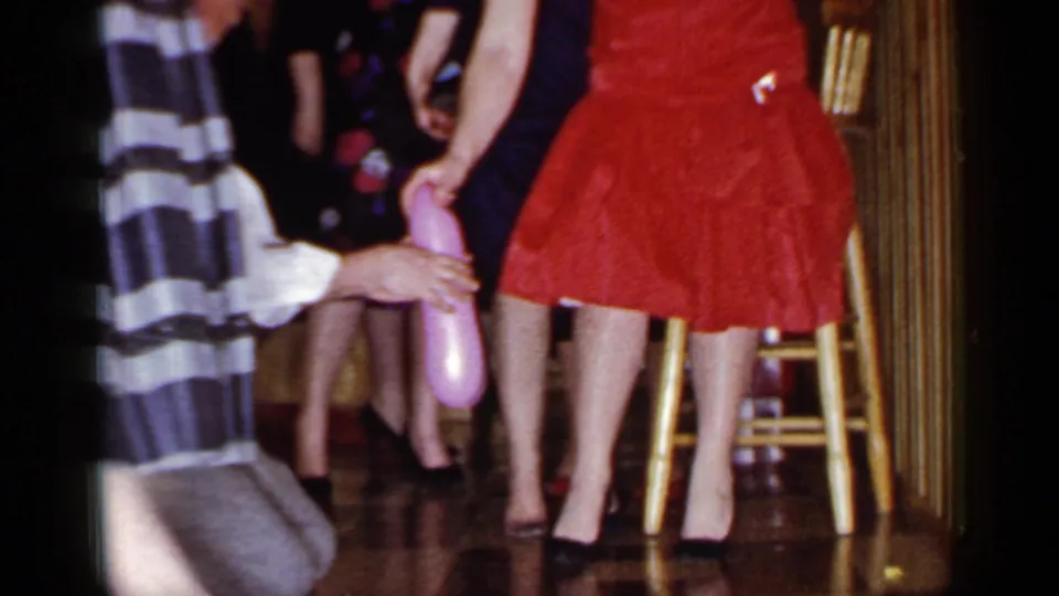 At the end of the 1966 Mineola clip, the kneeling man touches a woman's calf near a pink balloon and several women in dresses.