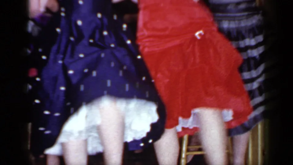1966 Mineola frame showing two women dancing with backs partly turned, red and navy dresses, and white ruffled underskirts.