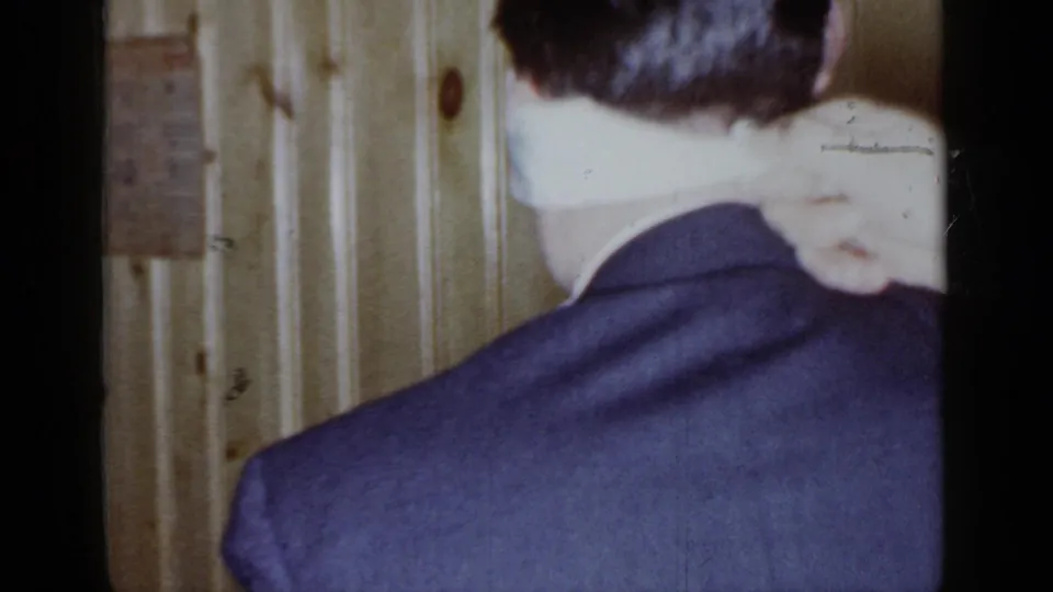 A suited adult is seen from behind while embracing another guest in a 1966 Mineola private party scene.