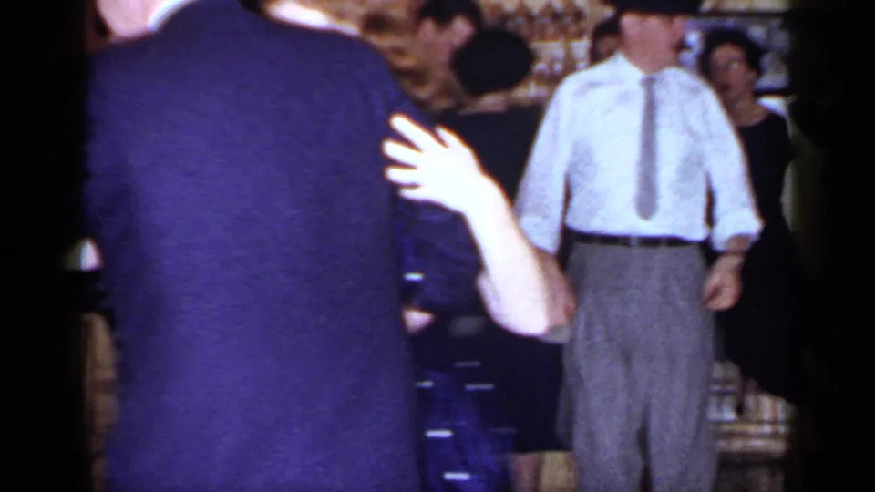 1966 Mineola frame with the dancing couple in the foreground and formally dressed guests standing nearby.