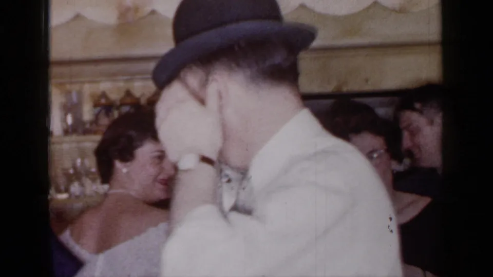 A man in a bowler-style hat and light jacket moves near women at the 1966 Mineola gathering.