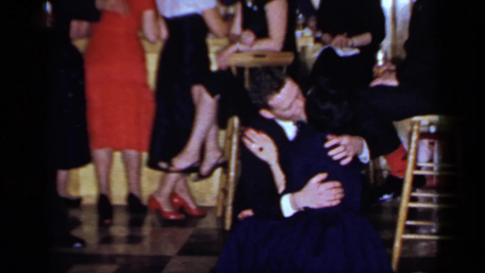 1960s Mineola club frame with a couple dancing low in the foreground, surrounded by bar stools, dresses, suits, and a checkered floor.