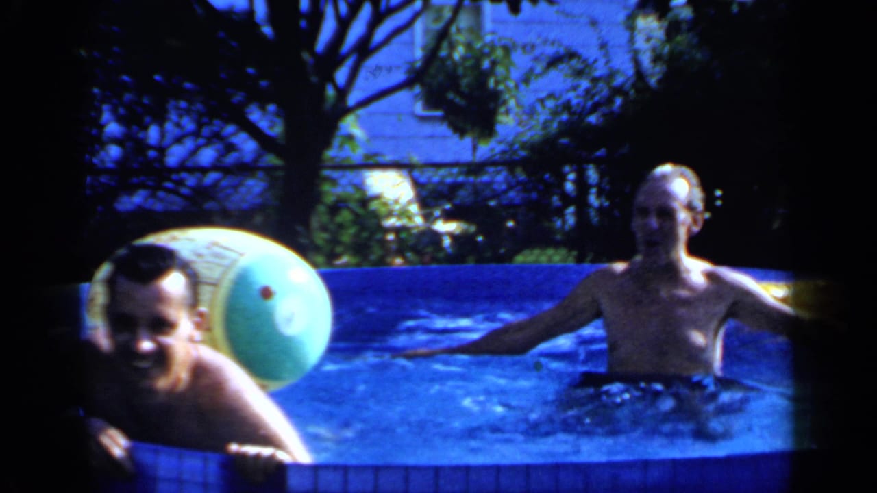 Two men in an above-ground pool with a large inflatable beach ball nearby.