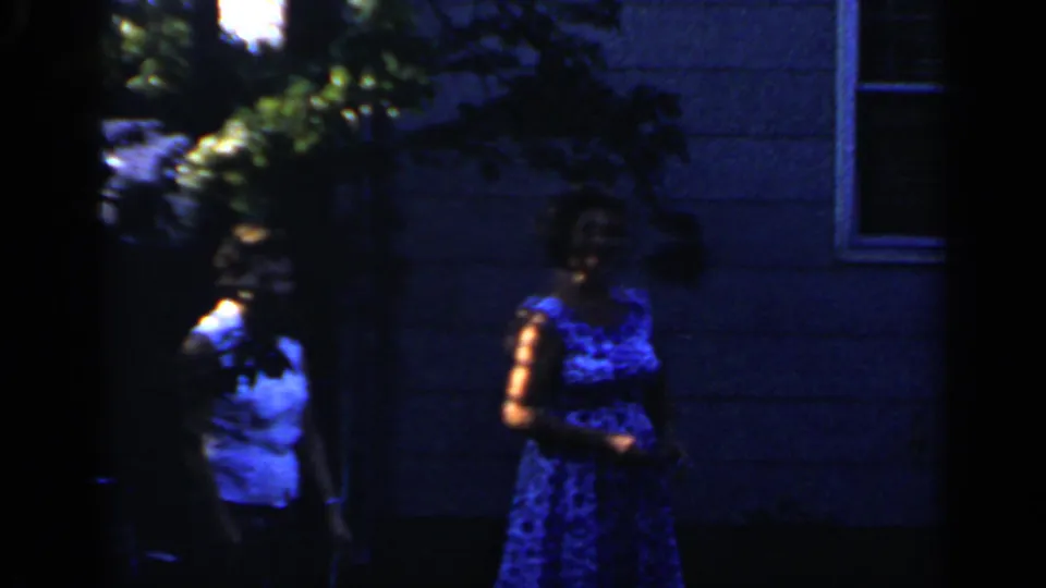 In the Mineola backyard footage, two women are visible in blue-toned shade near a house wall and foliage.