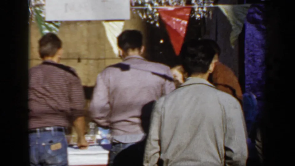 Mineola, New York 1966 home-movie frame of people standing from behind at a decorated outdoor event table.