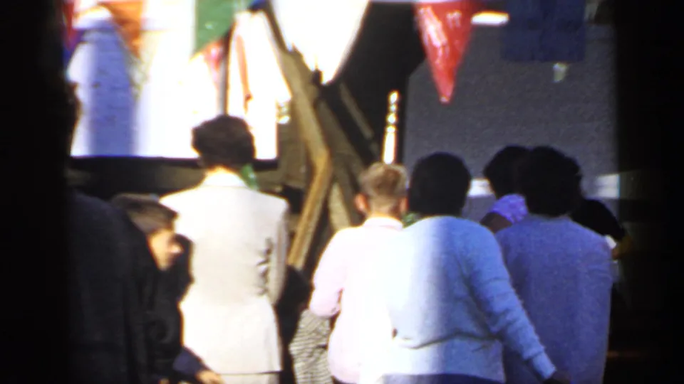 1966 Mineola 8mm frame showing adults from behind in a crowded outdoor fair-like setting.