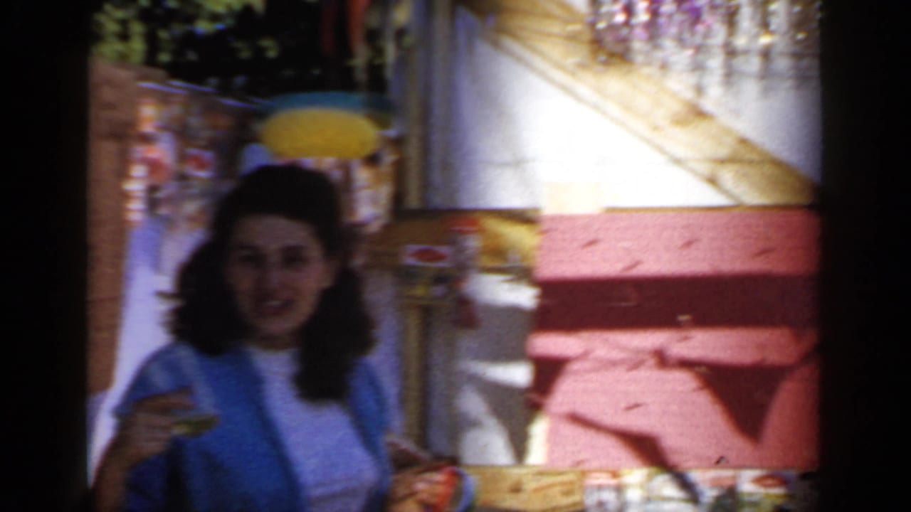 Young woman in a blue cardigan holds a ring at a carnival game booth.