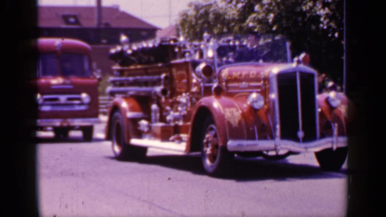 1966 Mineola, New York footage showing a red fire engine marked M.F.D. moving along a suburban street.