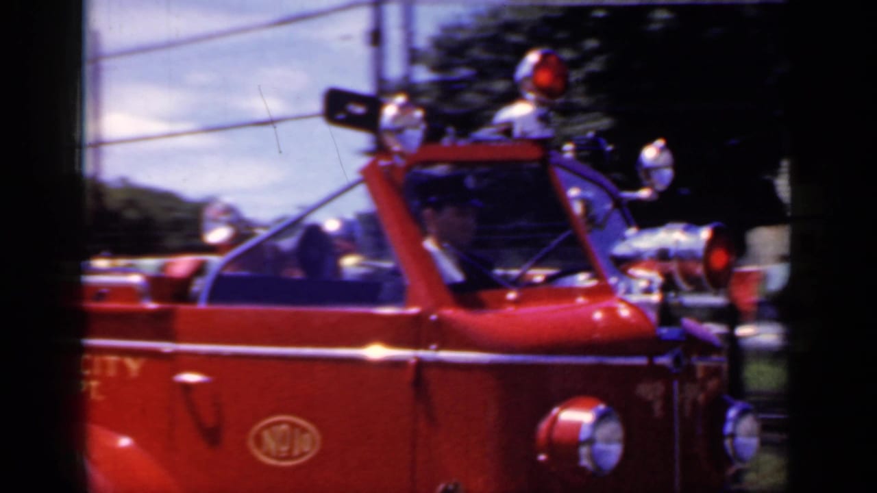 Close side view of a red fire truck with warning lights and chrome fixtures.