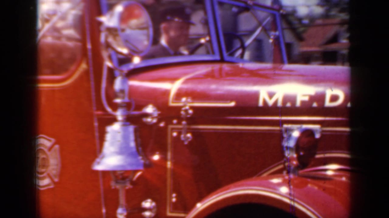 Close view of a red M.F.D. fire truck with chrome bell and gold trim.
