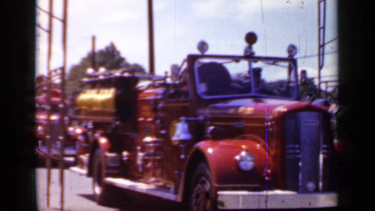 Red fire truck moving along a road with a gold tank behind the cab.