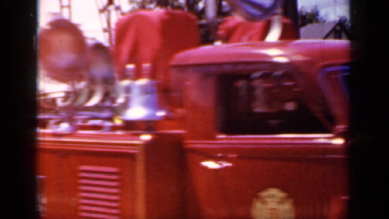 Close side view of a red fire truck with chrome bell and hose hardware.