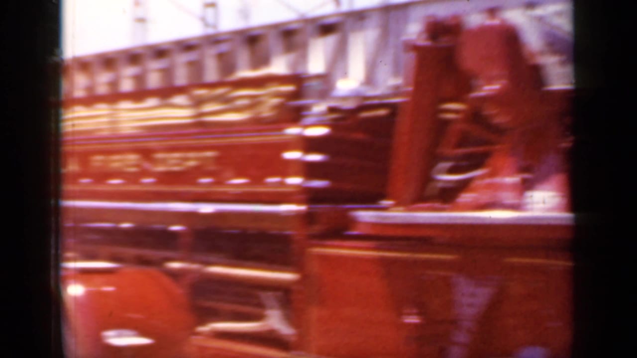 Red vintage fire truck passing close to the camera with riders blurred by motion.