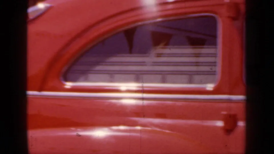 Close 1966 Mineola home-movie view of the red ambulance side, centered on the rear window and door panel.