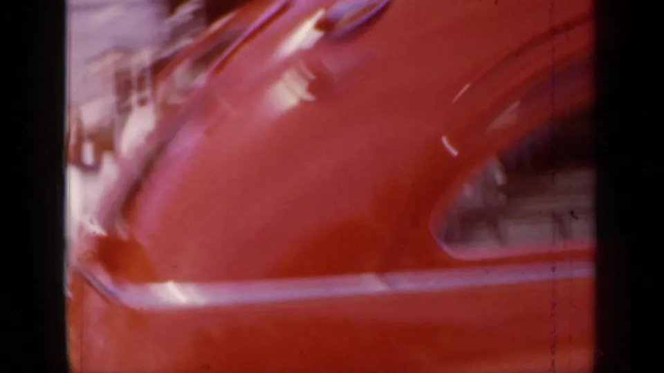 Motion-blurred rear-side detail of the red ambulance at the end of the 1966 Mineola street shot.