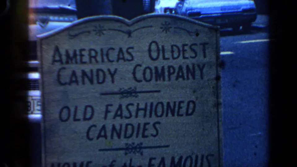 Closer 1968 Massachusetts view of the candy-company sign with legible old-fashioned candies text and street details behind it.