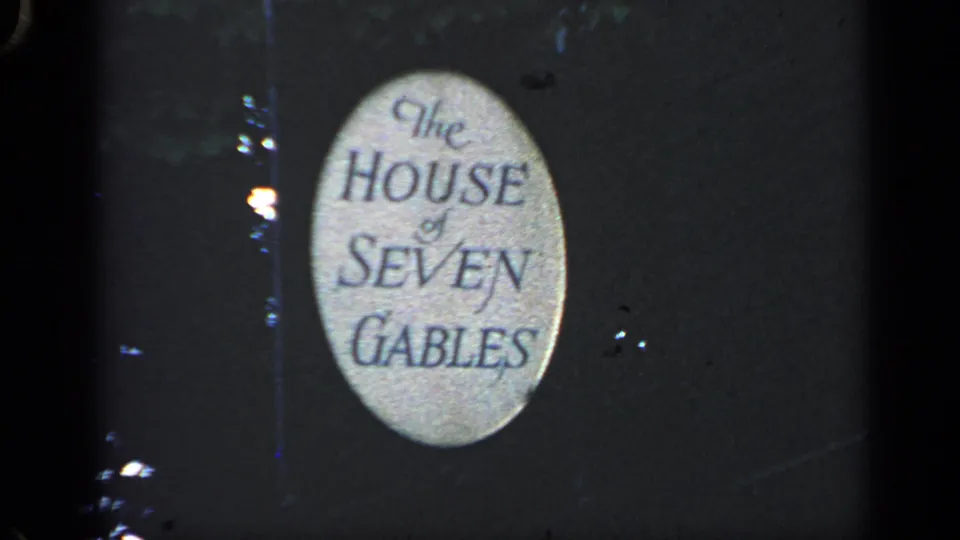 1968 Massachusetts 8mm frame centered on the oval sign for The House of Seven Gables in low light.