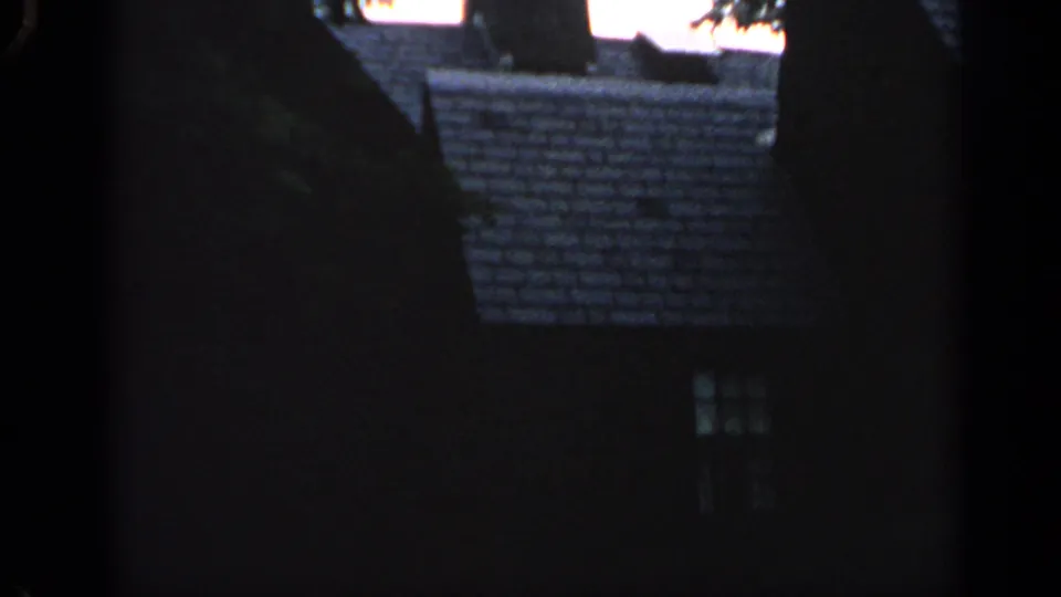 1968 Massachusetts 8mm frame showing dark residential rooflines, a faint lit window, and part of a parked car at night.