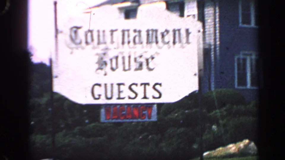 A sign reading Tournament House GUESTS with a red VACANCY notice appears beside the Massachusetts lodging exterior.