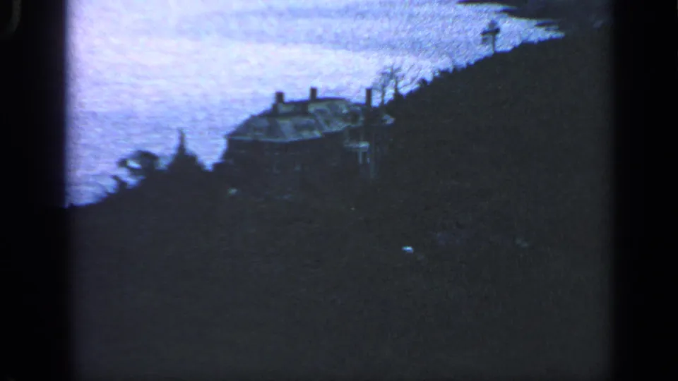 1968 8mm Massachusetts coastal view with a house partly silhouetted on the bluff and the ocean or bay behind it.