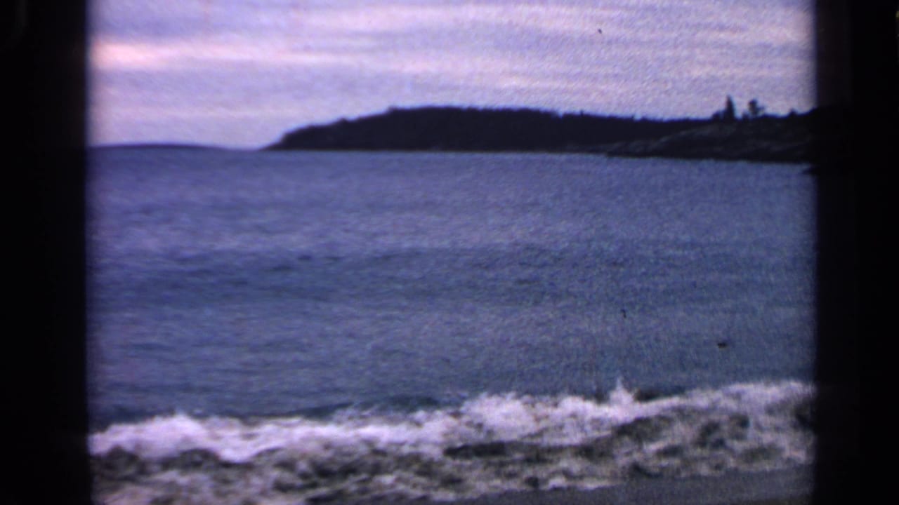 Breaking surf crosses the foreground beneath a distant dark shoreline.