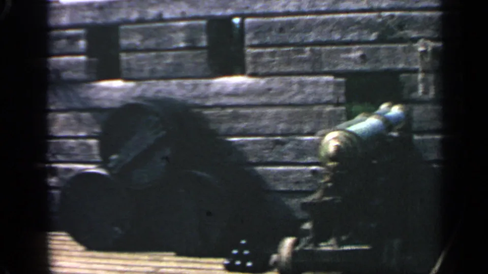 A closer 8mm view shows a cannon, stacked cannonballs, and weathered wooden planks at the Massachusetts replica colony site.