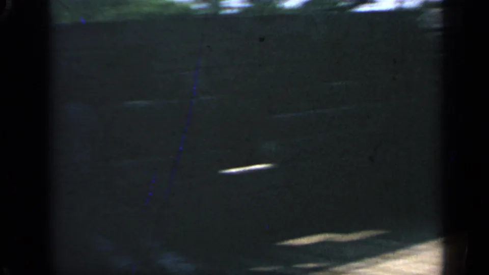 The final frame is a dim, partial view of the wooden wall area with strong shadow, film grain, and small bright light streaks.