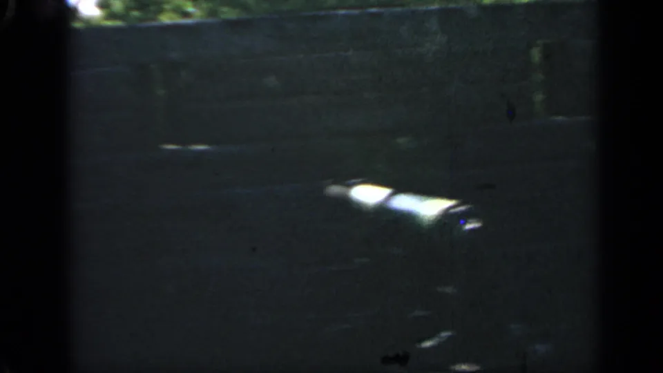 1969 Massachusetts 8mm frame showing a dark roofline or wall edge, dim sky, and heavy film grain.