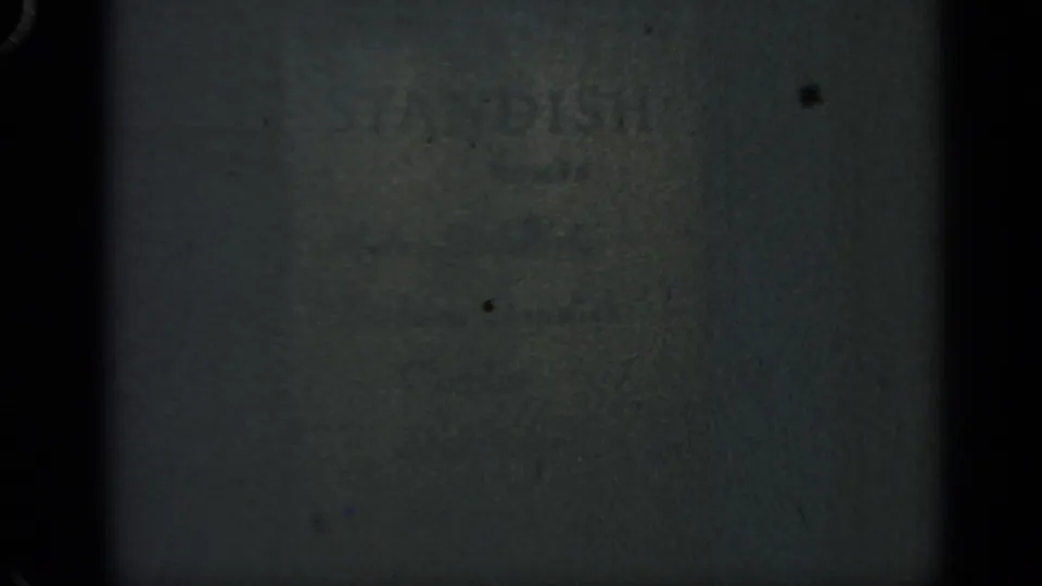 Dark 1969 Massachusetts 8mm frame with indistinct wall texture, soft focus, and visible film wear.