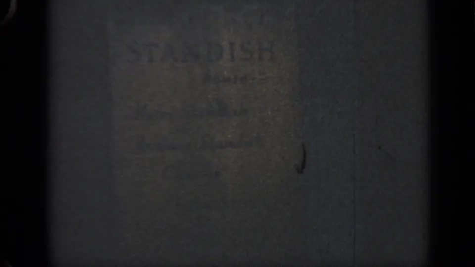 Close 1969 Massachusetts 8mm view of faded STANDISH lettering on a dark, textured wall surface.