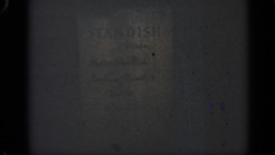 Close-up of faint STANDISH lettering on a dark textured surface in grainy 1969 Massachusetts 8mm footage.