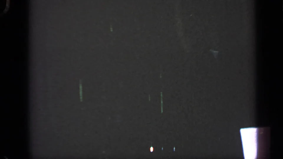 1969 Massachusetts 8mm frame showing a mostly shadowed view with part of a thatched roof structure at the upper right.