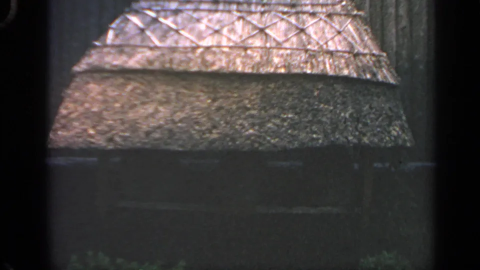 1969 Massachusetts 8mm frame showing the straw roof edge, crisscross framework, and weathered dark structural surfaces.