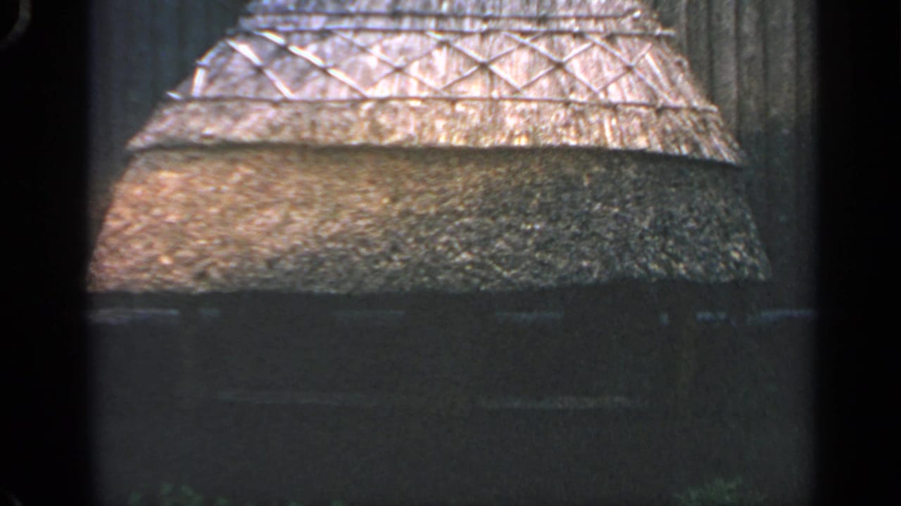 Thatched roof and dark wall of a rustic hut in low light.